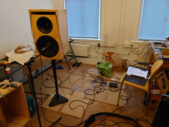 Bare plywood prototype cabinet on a stand during a REW measurement session