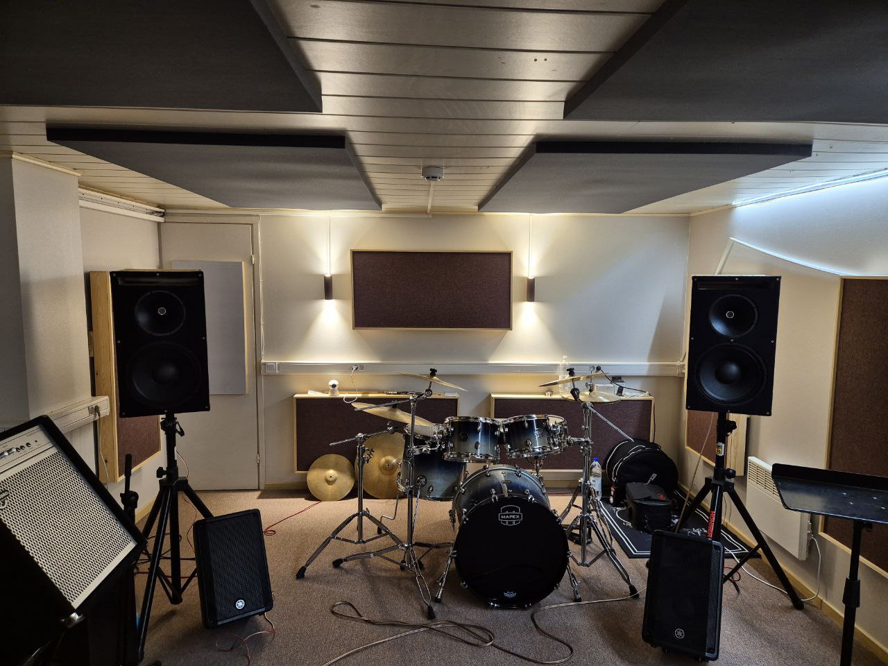 Finished rehearsal studio with drums set up, wall and ceiling absorbers visible
