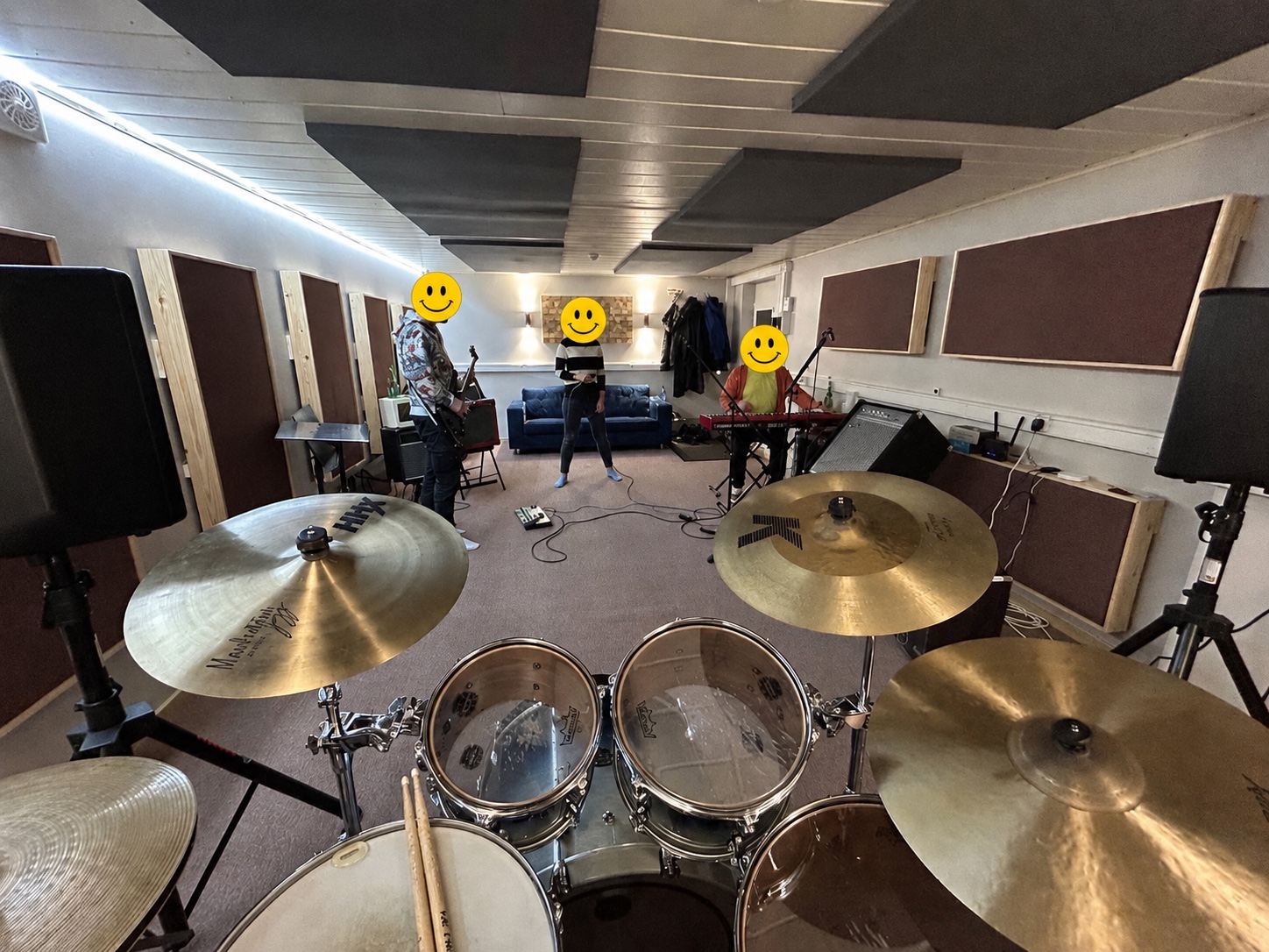 Drum-cam view of the studio in active use, band members anonymised